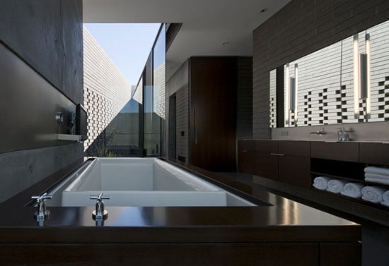 Modern bathroom with a large bathtub, long mirror, and open skylight