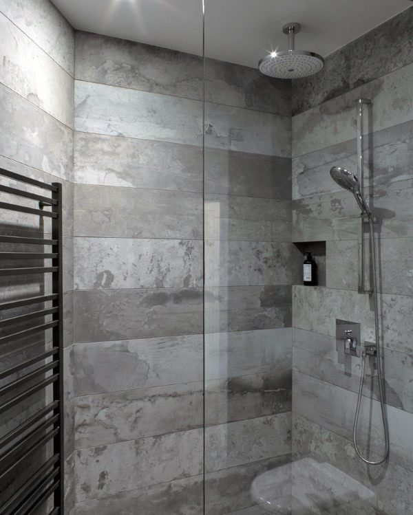 Gray tiled shower with rainfall showerhead and built-in shelf.