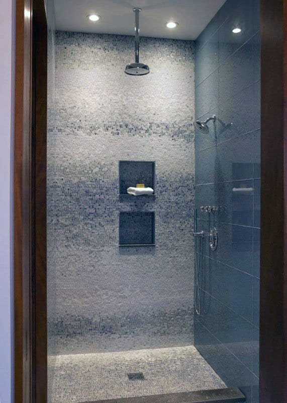 Modern shower with blue mosaic tiles, built-in shelves, and rainfall showerhead.