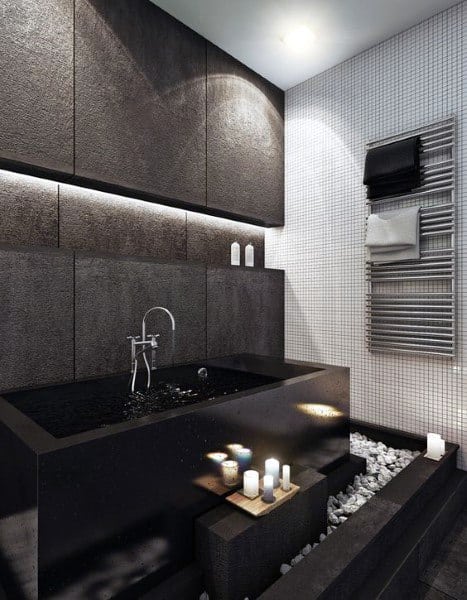 Japanese-inspired bathroom with black bathtub, pebbles, and candlelit decor.