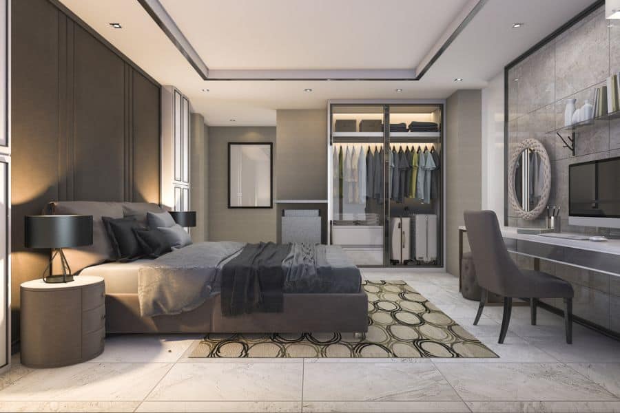 Luxurious bedroom with glass wardrobe, work desk, and elegant gray decor.