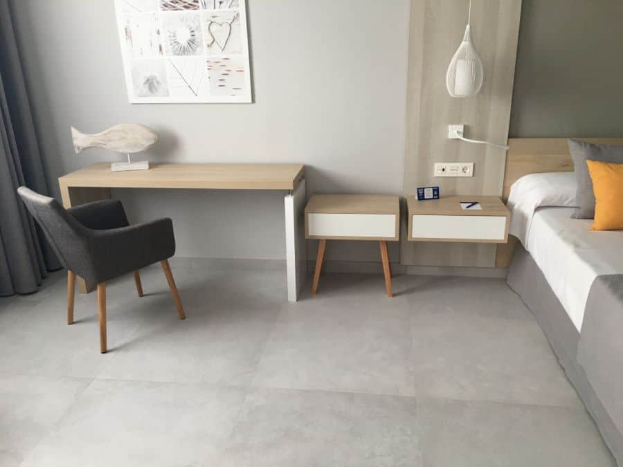 Minimalist bedroom with sleek desk, gray chair, and floating bedside tables.