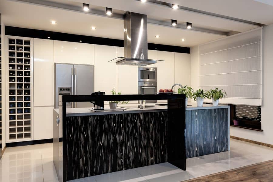 Modern kitchen with black island, white cabinets, stainless steel appliances, and wine rack.