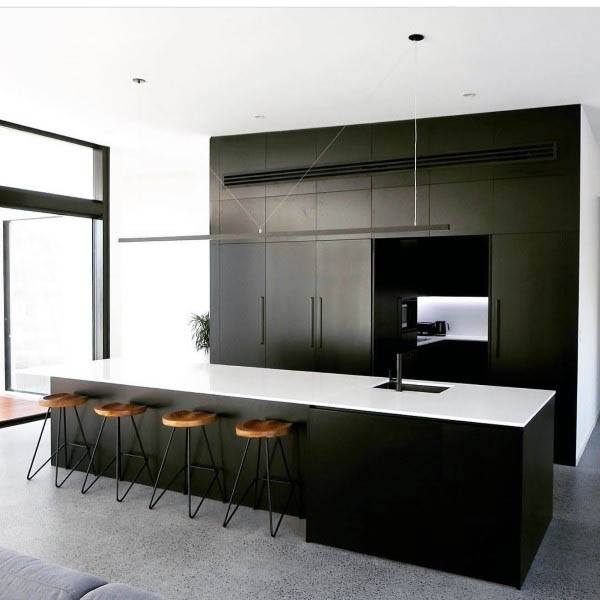 Modern black kitchen with white countertop, wooden barstools, and minimalist lighting.