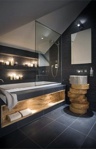 Rustic bathroom with candles, dark walls, glass shower, and wooden sink stand