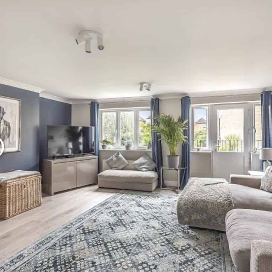 Spacious living room with grey sofas, navy curtains, and a patterned blue rug.