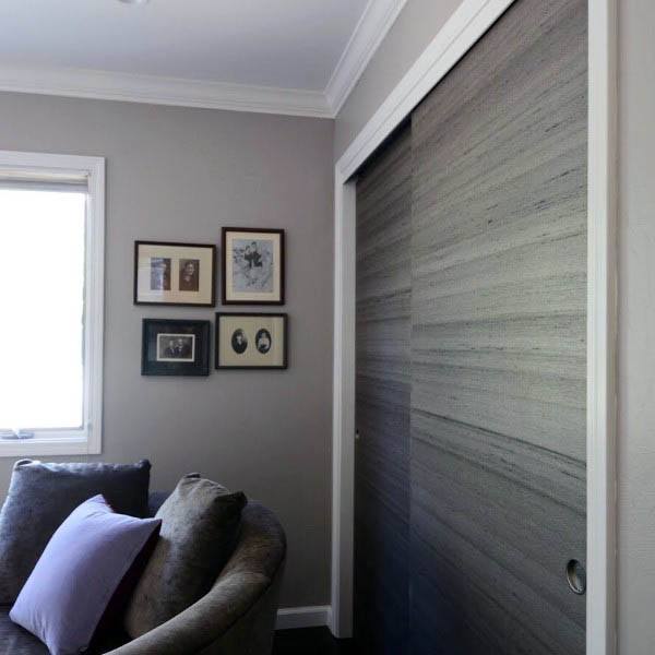 A modern sliding closet door with a textured wood finish, seamlessly blending into a neutral-toned room for a sleek, contemporary look