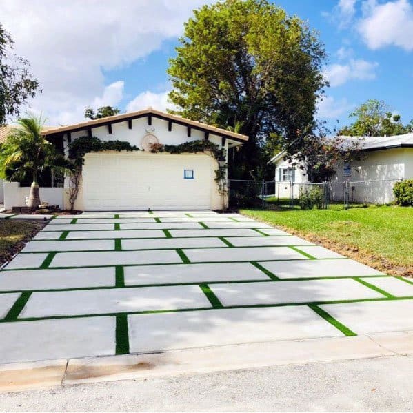 Modern single-story home with a concrete driveway featuring grass strips for a clean, stylish look.