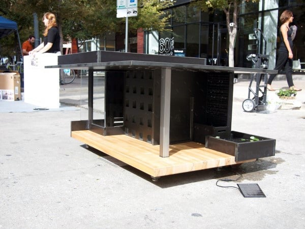 A modern, contemporary dog house featuring black painted walls and sleek, minimalist design with a wooden base