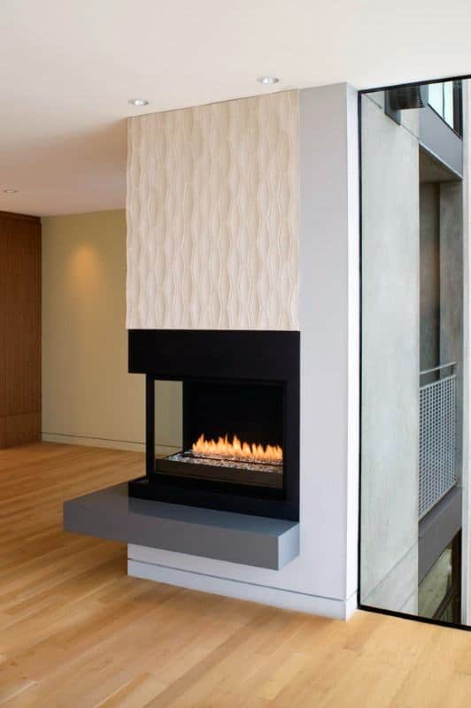 Modern corner fireplace with glass panels, black metal frame, and light wood flooring.