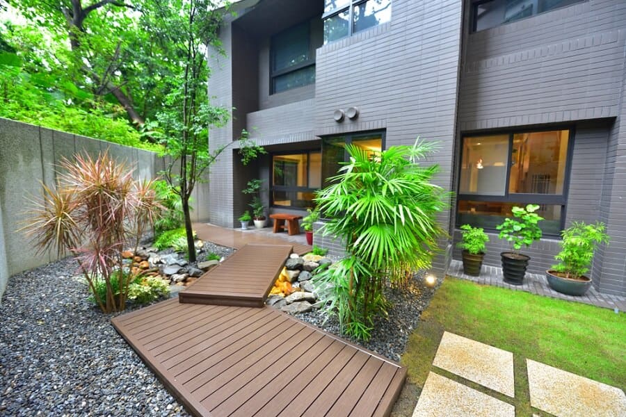 Modern garden with wooden walkways, lush plants, and a brick building