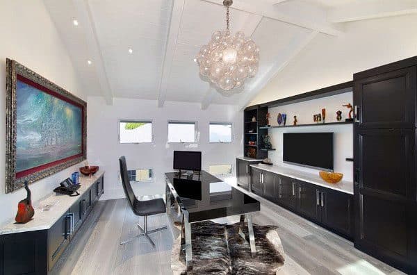 Bright modern home office with black desk, art display, and bubble chandelier.
