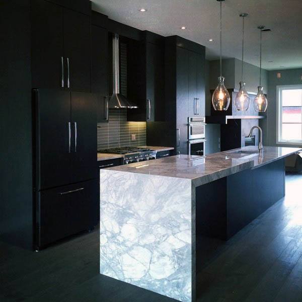 Modern kitchen with black cabinets, marble island, pendant lighting, and stainless steel accents.