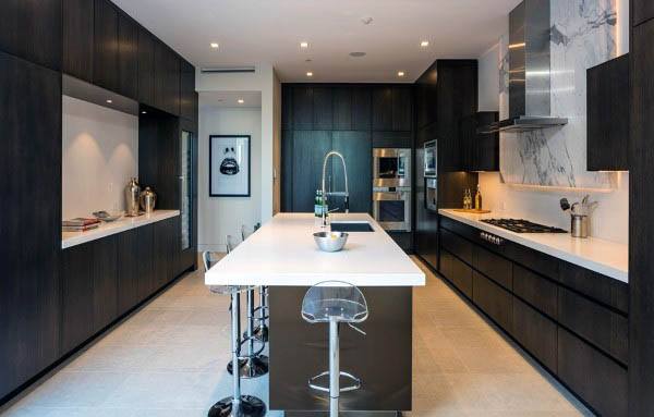 Contemporary kitchen with dark wood cabinets, white countertops, and marble backsplash.