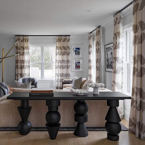 Modern dining and living space with geometric print curtains, statement furniture, and neutral tones.