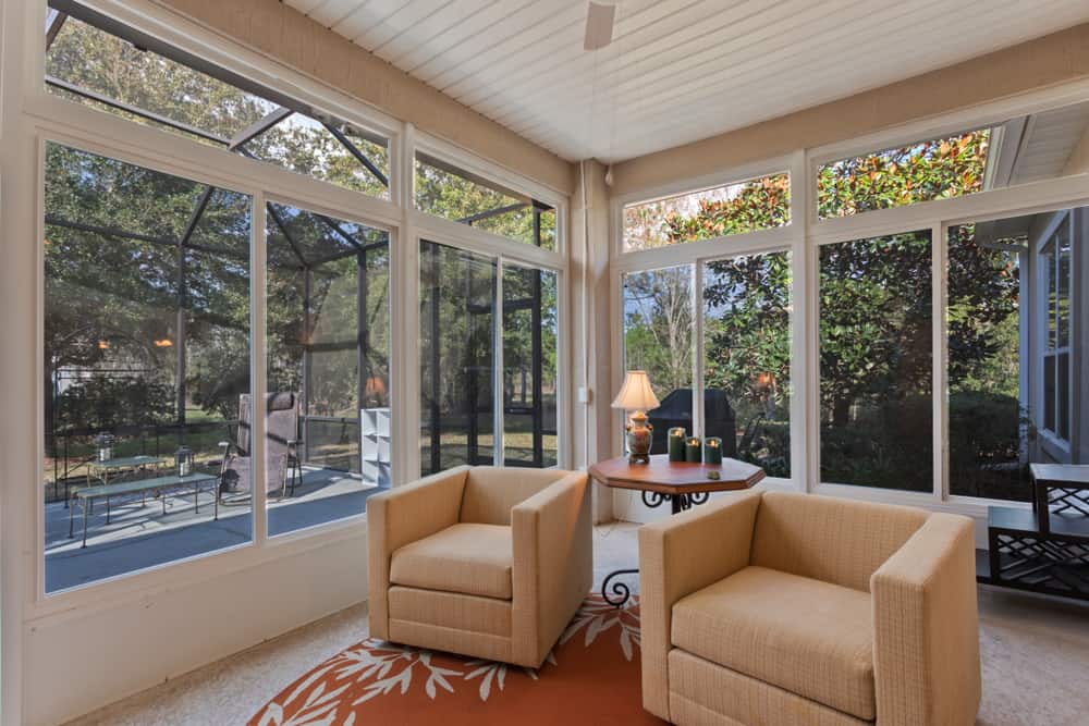 modern enclosed patio ceiling fan two lounge chairs wood table candles 