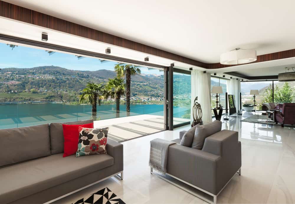 modern enclosed patio gray sofa and lounge chair marble floor lake view 