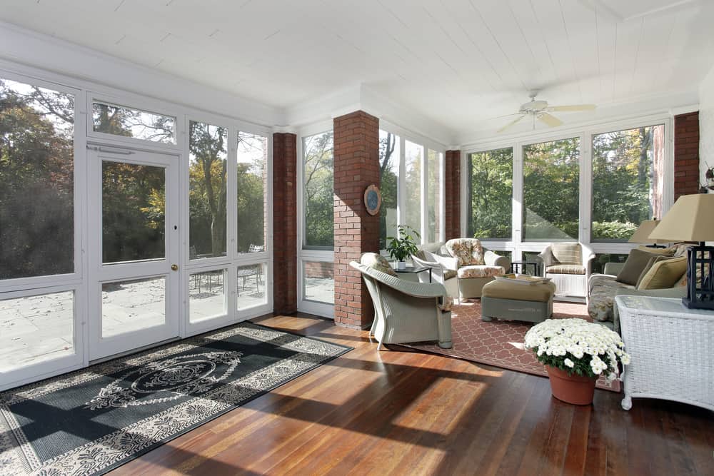 modern enclosed wicker furniture pattern rug wood deck exposed brick columns 