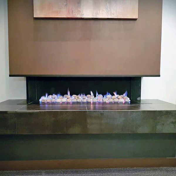 Modern fireplace featuring a sleek concrete ledge with decorative stones and a warm, minimalistic aesthetic.
