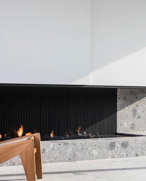 A sleek modern fireplace featuring a black fluted design and a terrazzo base.