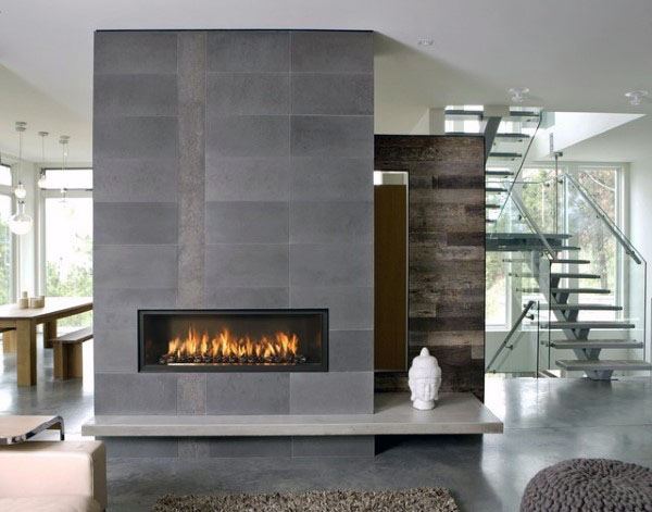 Sleek modern fireplace with gray tiled surround, open floor plan, and glass staircase.