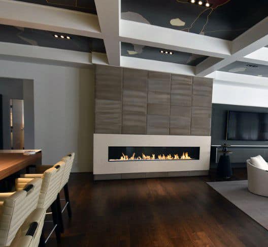 Modern living room with linear fireplace, wood paneled wall, and bar seating area.