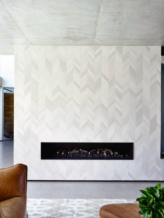 Modern linear fireplace with herringbone patterned white wall and minimalist decor.