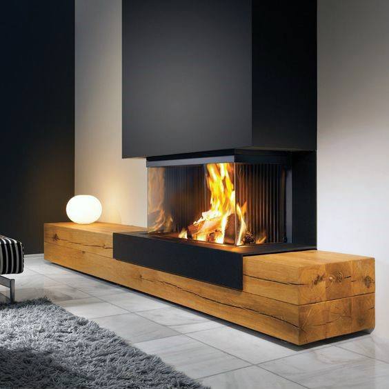 Modern fireplace with black enclosure, glass panels, and rustic wooden base design.