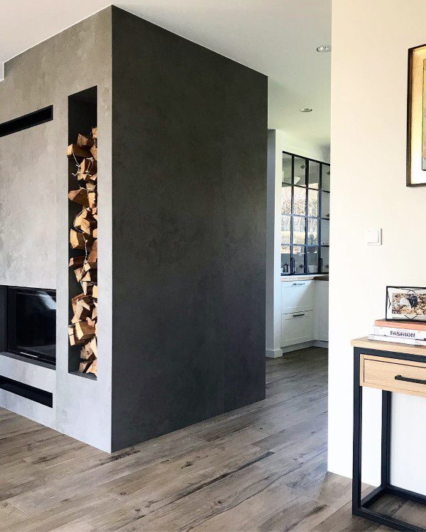 Modern fireplace with sleek black finish, built-in firewood storage, and minimalist interior design.