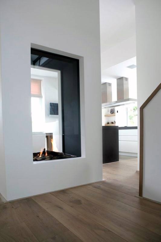 Minimalist see-through fireplace connecting living area and modern kitchen design.
