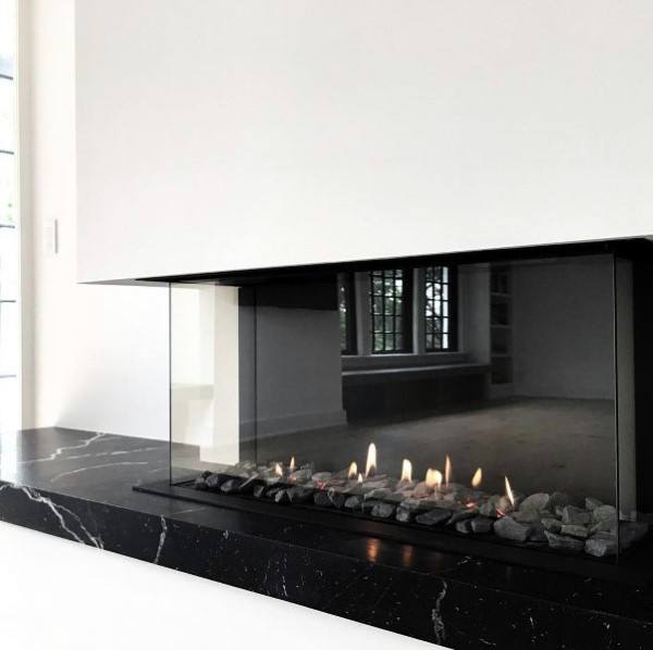 A modern see-through fireplace with a black marble base offers a chic and functional way to connect spaces while adding warmth and sophistication.