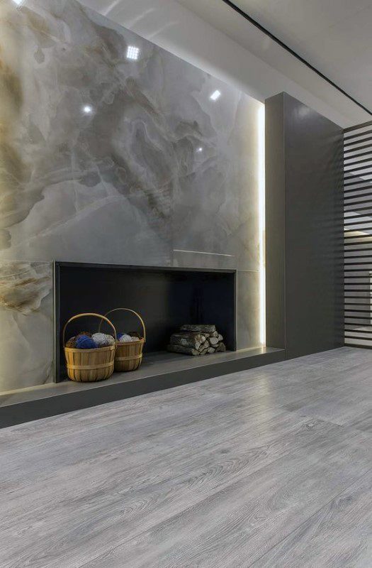 A luxurious fireplace design featuring a stunning marble accent wall illuminated by subtle lighting, creating a refined and cozy atmosphere.