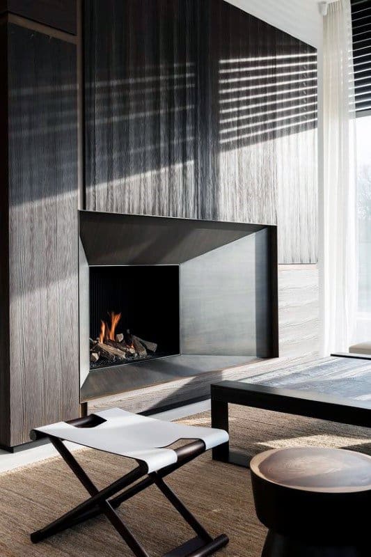 A sleek modern fireplace with dark wood panels and metallic accents, creating a sophisticated living space.