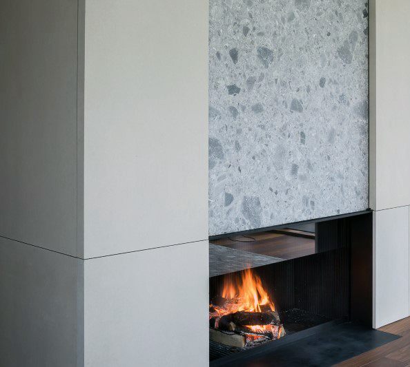 A sleek modern fireplace with textured stone detail, combining minimalism and natural elements for a cozy ambiance.