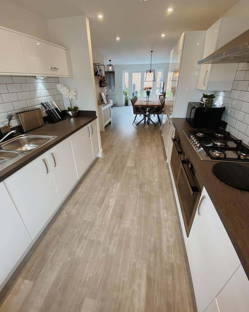 modern galley kitchen white cabinets brown countertop vinyl flooring