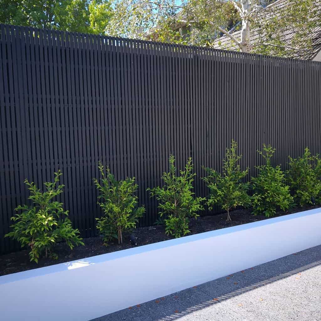 modern garden metal wall white retaining wall green shrubs