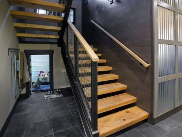 Wooden floating stairs with black metal railing and dark tile flooring in a modern hallway design.