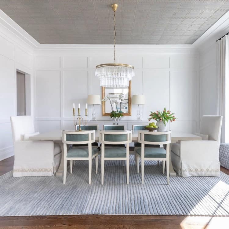 A modern dining room with a textured gray ceiling, elegant furniture, and a crystal chandelier, creating a sophisticated and stylish atmosphere