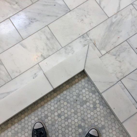 Consider using sneakers with white or light-colored soles to maintain a seamless look while providing comfort amidst the elegant mix of white marble and hexagonal mosaic tiles