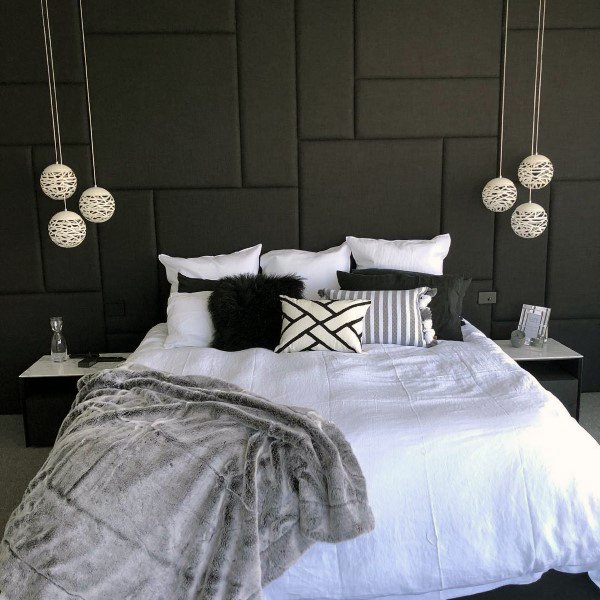 Modern bedroom with black panel headboard, white bedding, and pendant lights.
