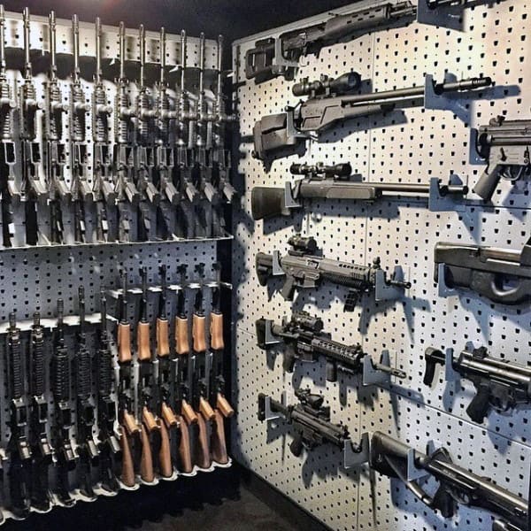 Gun room with pegboard walls displaying rifles, shotguns, and pistols in a compact layout.