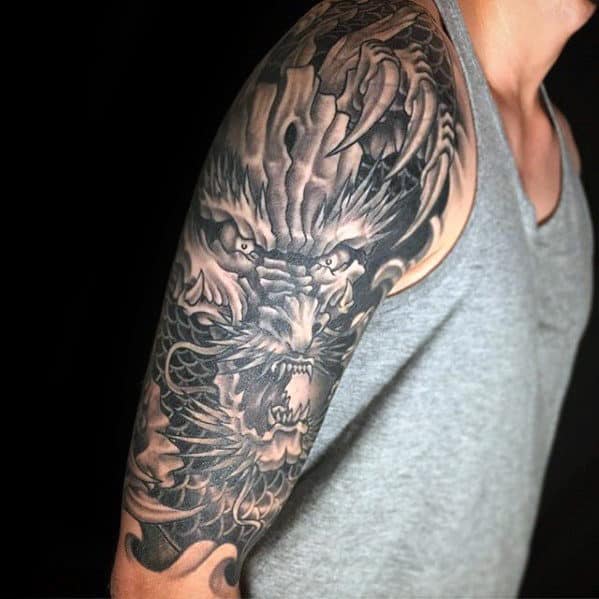 Arm with a detailed dragon tattoo in black and gray ink