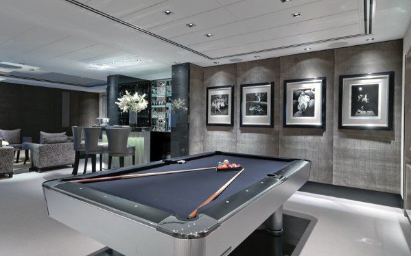 Modern billiard room with sleek pool table bar area and framed wall art.