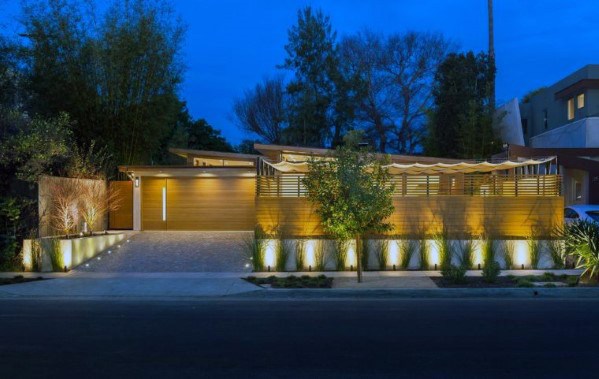Modern driveway with ambient lighting along the perimeter, highlighting the sleek wooden fence and surrounding landscaping at night