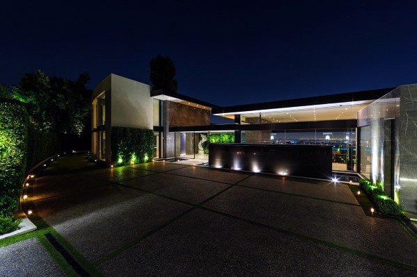 Contemporary driveway with sleek ground lighting, highlighting the modern architecture and surrounding greenery at night