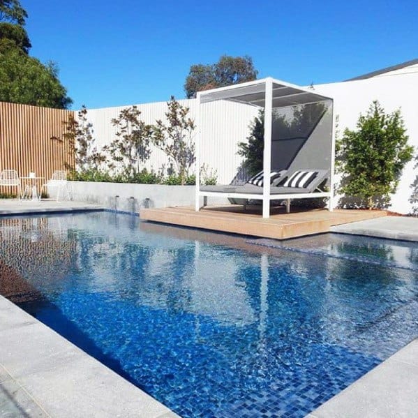 A modern backyard with a pool, a shaded lounge area, and minimalistic landscaping