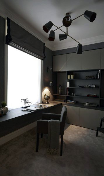 Dark modern home office with built-in desk, sleek shelves, and statement lighting fixture.
