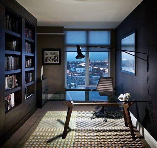 Modern home office with glass desk, bookshelf, floor lamp, and city night view.