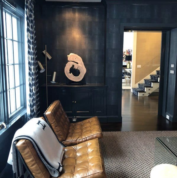 Cozy home office lounge with leather chairs, dark walls, and artistic decor accents.