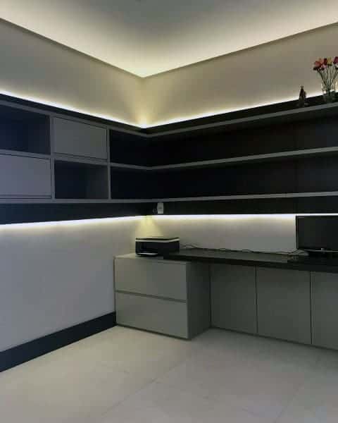 Minimalist modern home office featuring custom LED lighting, sleek shelving, and a built-in desk.
